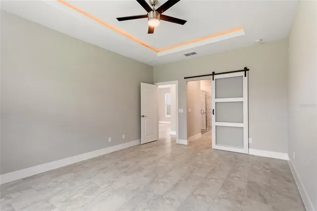 an empty room with ceiling fan and windows