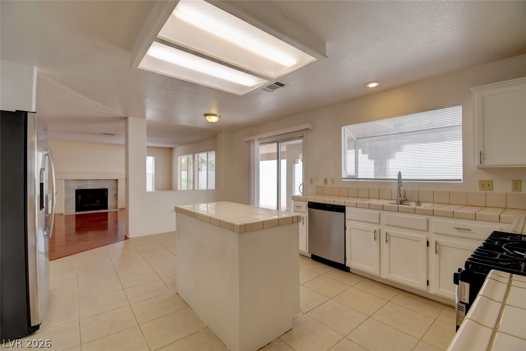5 Tarryall Terrace Henderson, NV 89074 - Photo 24 of 44 A well-lit kitchen with a central island seamlessly transitions into the adjoining living space, featuring a fireplace.