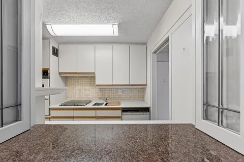 a view of kitchen with stainless steel appliances granite countertop a refrigerator and white cabinets