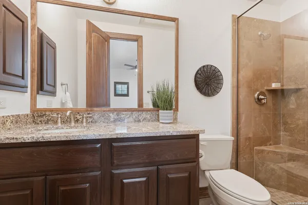 a bathroom with a granite countertop sink a toilet and shower