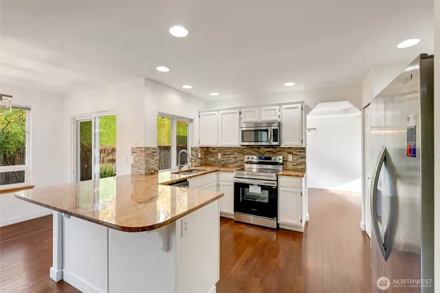 a kitchen with stainless steel appliances granite countertop a sink a stove and a refrigerator
