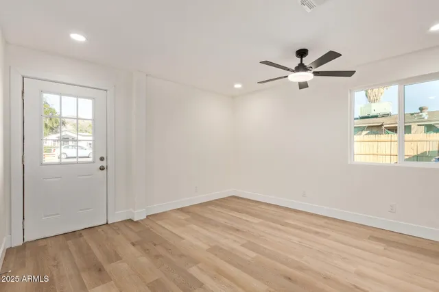 a view of empty room with wooden floor and fan