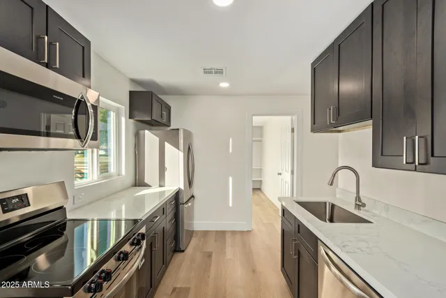 a kitchen with stainless steel appliances granite countertop a sink stove and refrigerator