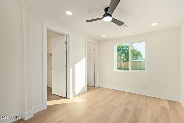 an empty room with a ceiling fan and a window