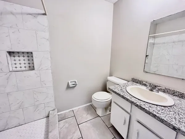 a bathroom with a granite countertop sink a toilet and a mirror