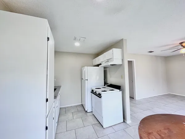 a view of kitchen with refrigerator and white cabinets