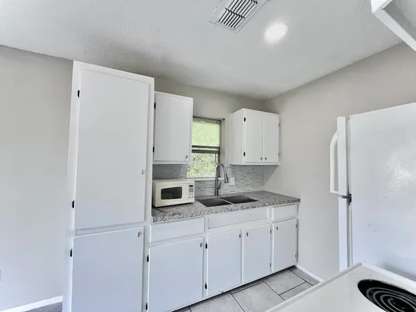 a kitchen with white cabinets and refrigerator