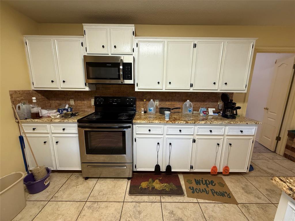 3016 County Road 4405 Commerce, TX 75428 - Photo 15 of 40 a kitchen with stainless steel appliances white cabinets and a stove a sink
