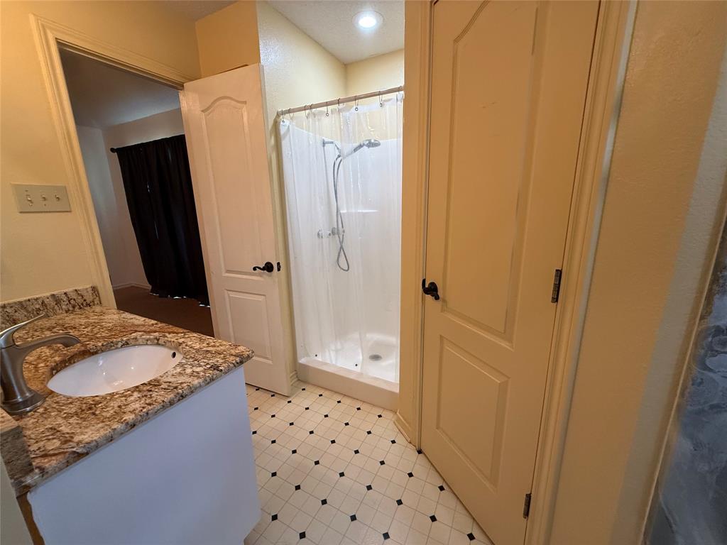 3016 County Road 4405 Commerce, TX 75428 - Photo 7 of 40 a bathroom with a granite countertop sink a mirror a shower and a sink