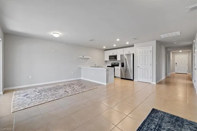 a view of kitchen with refrigerator and white cabinets