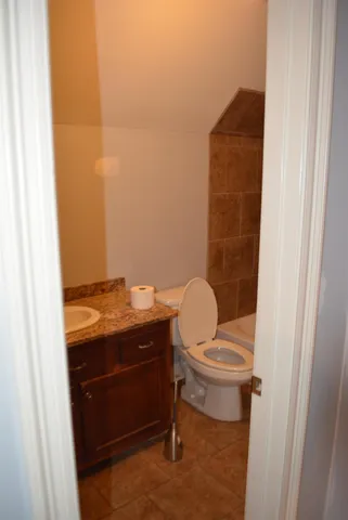 a bathroom with a granite countertop sink and a toilet