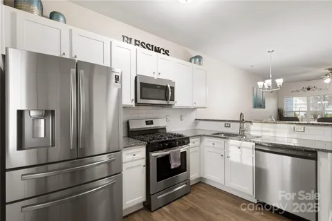 a kitchen with cabinets stainless steel appliances and wooden floor