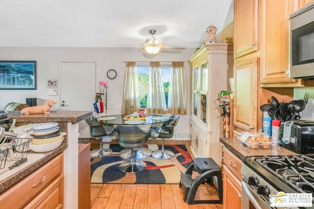 a view of a dining room with furniture one side kitchen view and wooden floor