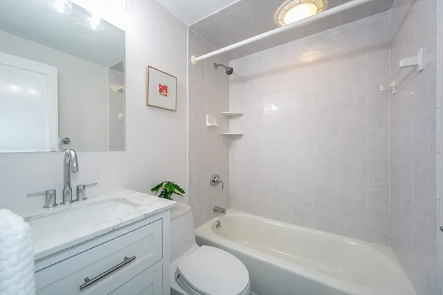 a bathroom with a granite countertop sink a toilet and shower