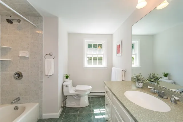 a bathroom with a granite countertop toilet sink and mirror