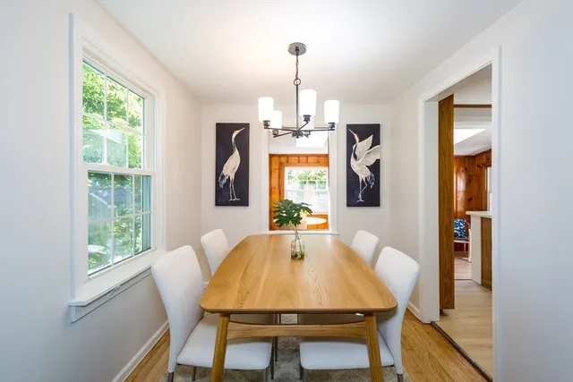 a dining room with chandelier and wooden floor