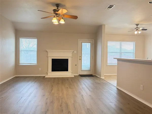 a view of an empty room with a window and wooden floor