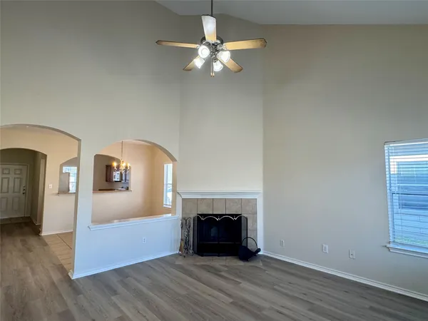 a view of an empty room with wooden floor fireplace and a window