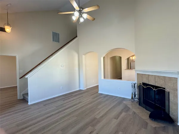 a view of an empty room with wooden floor fireplace and a window