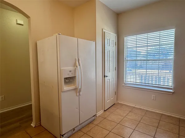 a view of an empty room with window and refrigerator