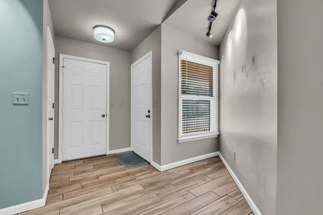 a view of an empty room with wooden floor and a window