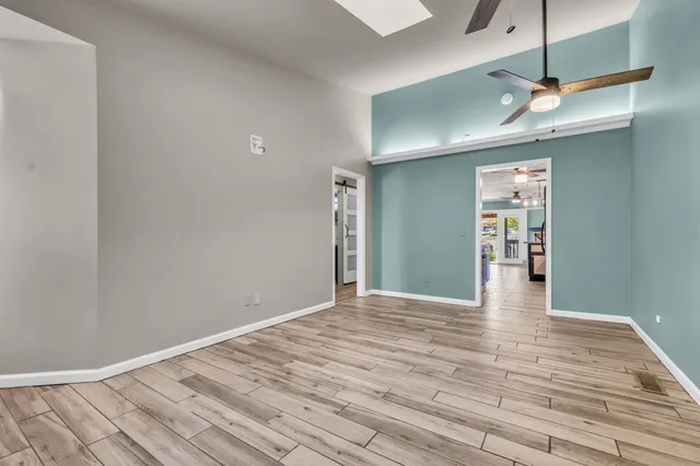 a view of an empty room with wooden floor and a window