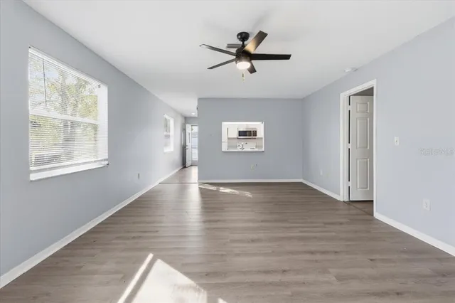 a view of empty room with wooden floor and fan