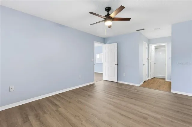 an empty room with wooden floor and a ceiling fan