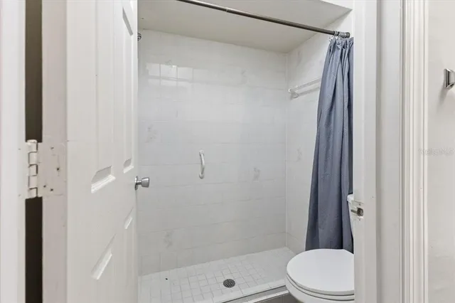 a bathroom with a shower a toilet and a glass door
