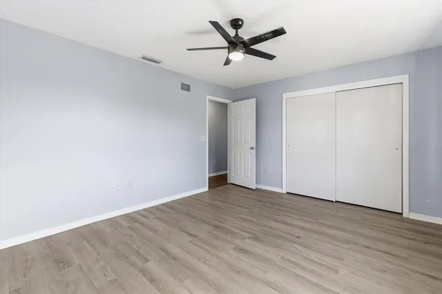 an empty room with wooden floor and ceiling fan