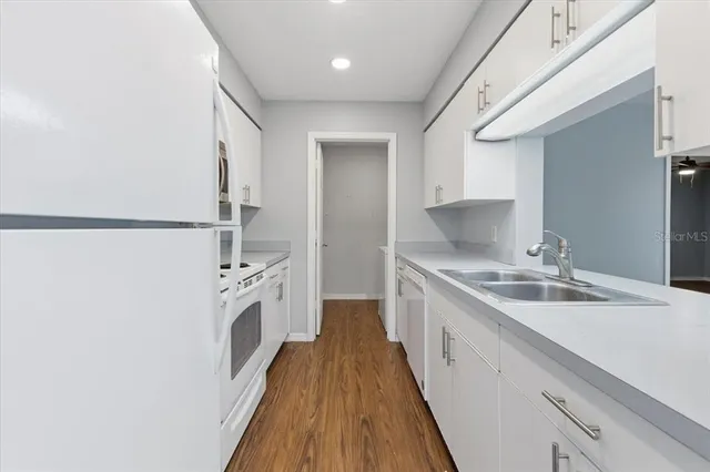 a kitchen with a sink a refrigerator and white cabinets