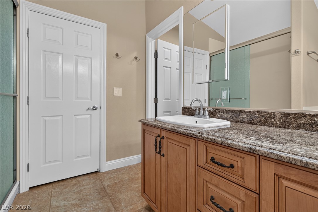 818 Manor Shores Road Henderson, NV 89002 - Photo 21 of 35 Granite counters and a warm wood vanity elevate this functional bathroom space.