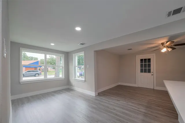 an empty room with wooden floor and windows
