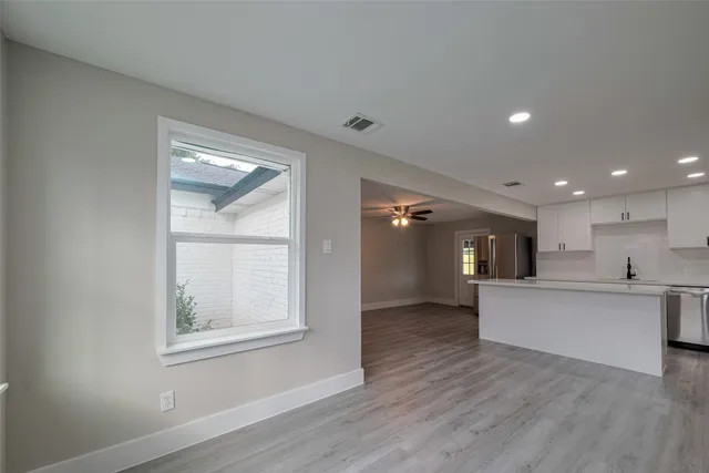 a view of a kitchen with kitchen island wooden floors and stainless steel appliances