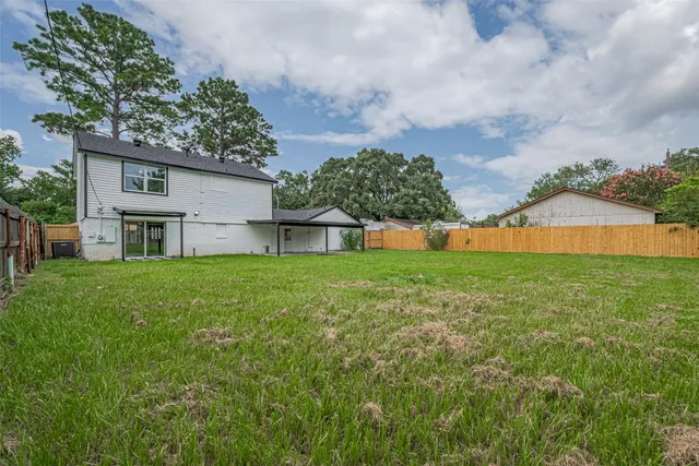 a view of a house with a yard and a large tree