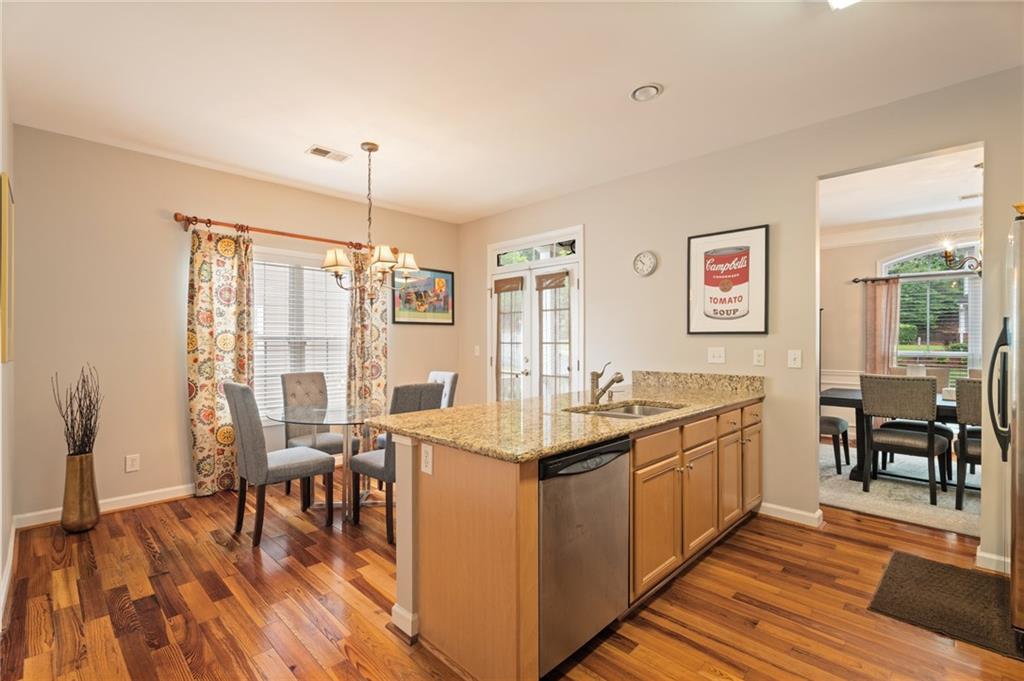 878 Scales Road Suwanee, GA 30024 - Photo 8 of 17 a kitchen with stainless steel appliances granite countertop a stove oven a dining table and chairs with wooden floor