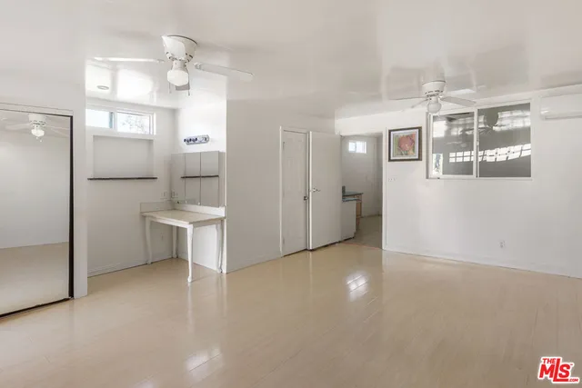 an empty room with windows and ceiling fan