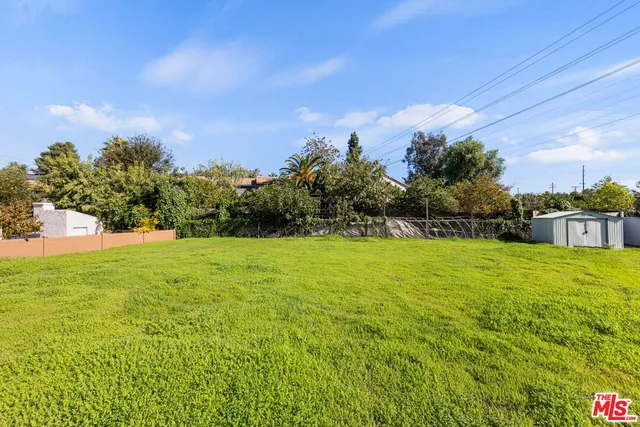 a view of a white house with a big yard and large trees