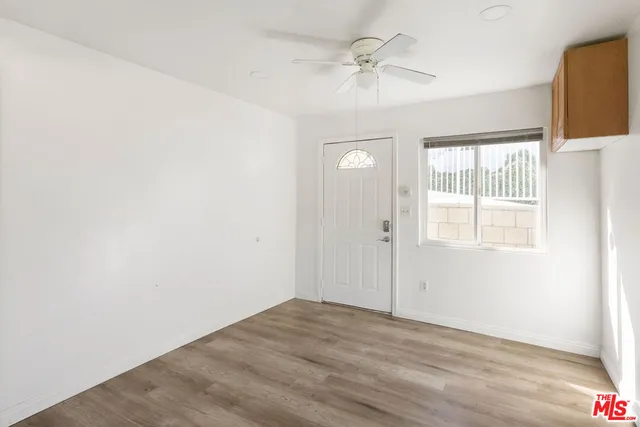 an empty room with wooden floor fan and windows