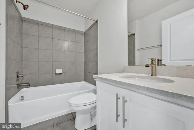 a bathroom with a granite countertop bathtub shower sink vanity mirror and toilet