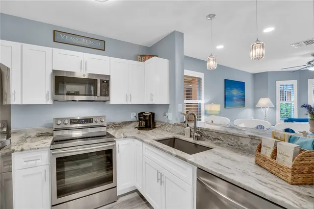 a kitchen with granite countertop a sink a stove and microwave