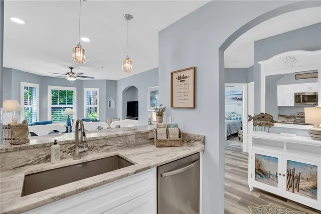 a kitchen with granite countertop a sink dishwasher and white cabinets with wooden floor