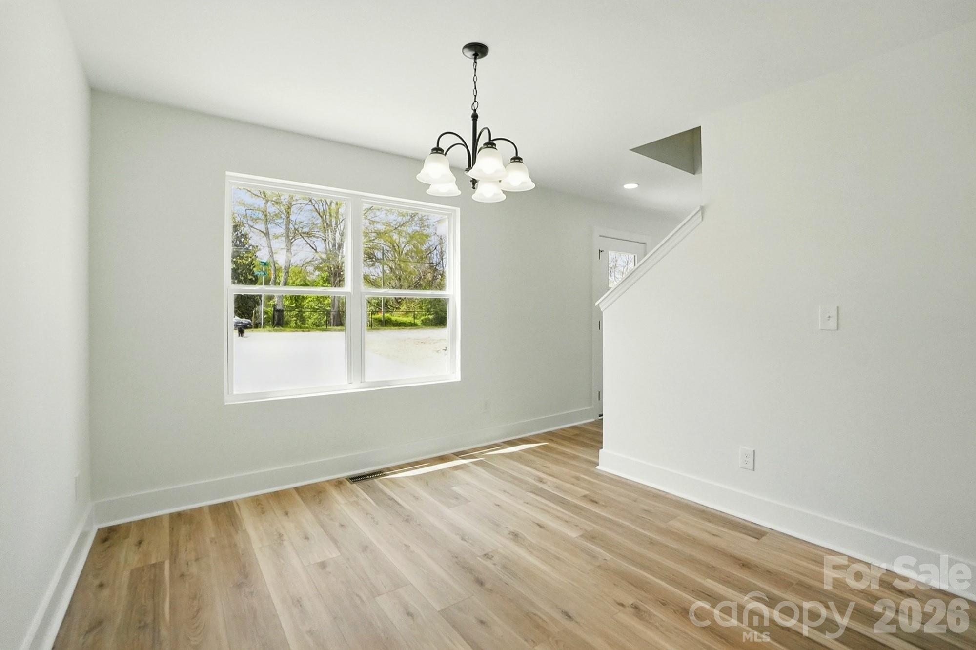 274 Bellhaven Place Northwest Concord, NC 28027 - Photo 13 of 27 an empty room with wooden floor chandelier and windows