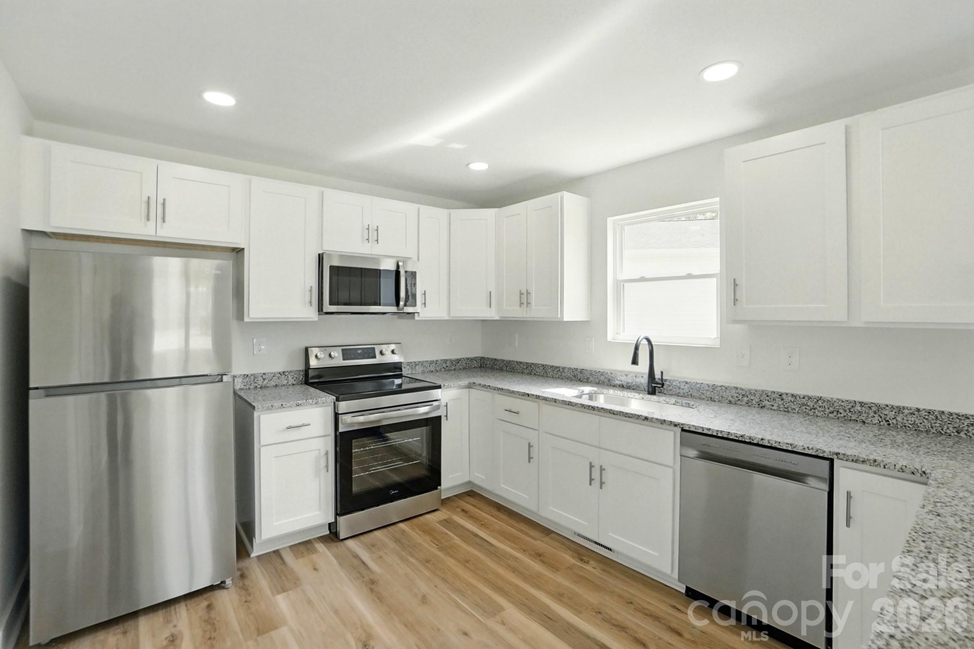 274 Bellhaven Place Northwest Concord, NC 28027 - Photo 8 of 27 a kitchen with a sink a refrigerator a microwave and cabinets