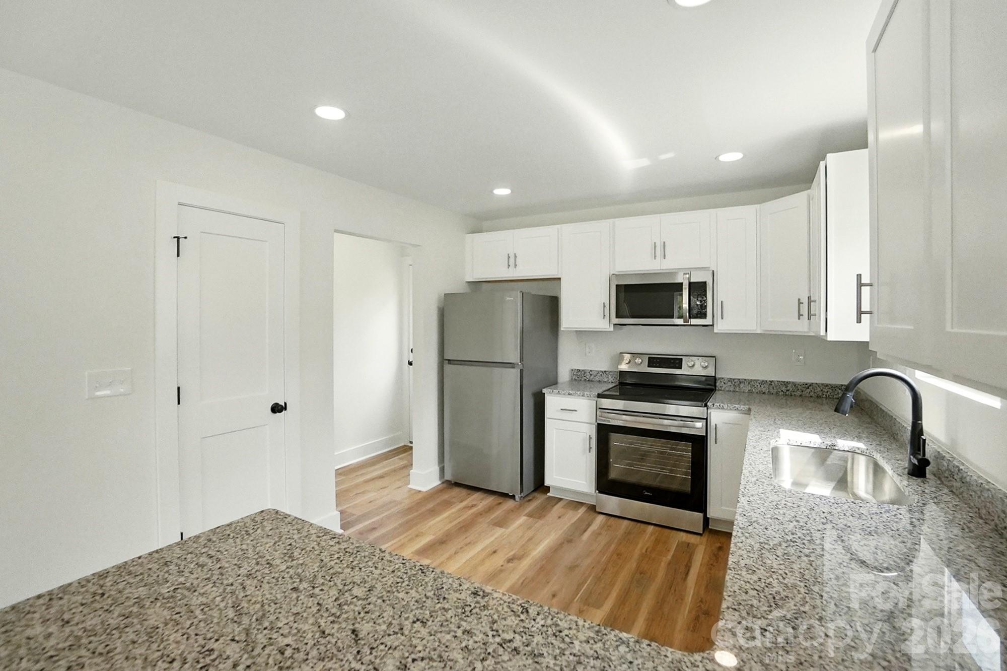 274 Bellhaven Place Northwest Concord, NC 28027 - Photo 10 of 27 a kitchen with granite countertop a refrigerator and a stove top oven