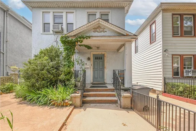 a view of a house with a small yard and plants and wooden fence