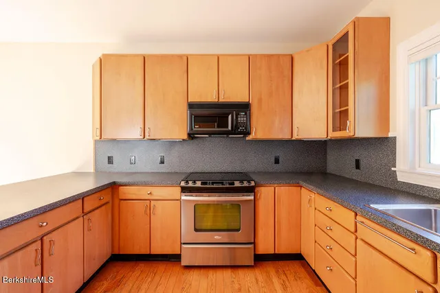 a kitchen with granite countertop a stove a sink and a microwave