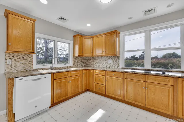 a kitchen with granite countertop sink window and cabinets