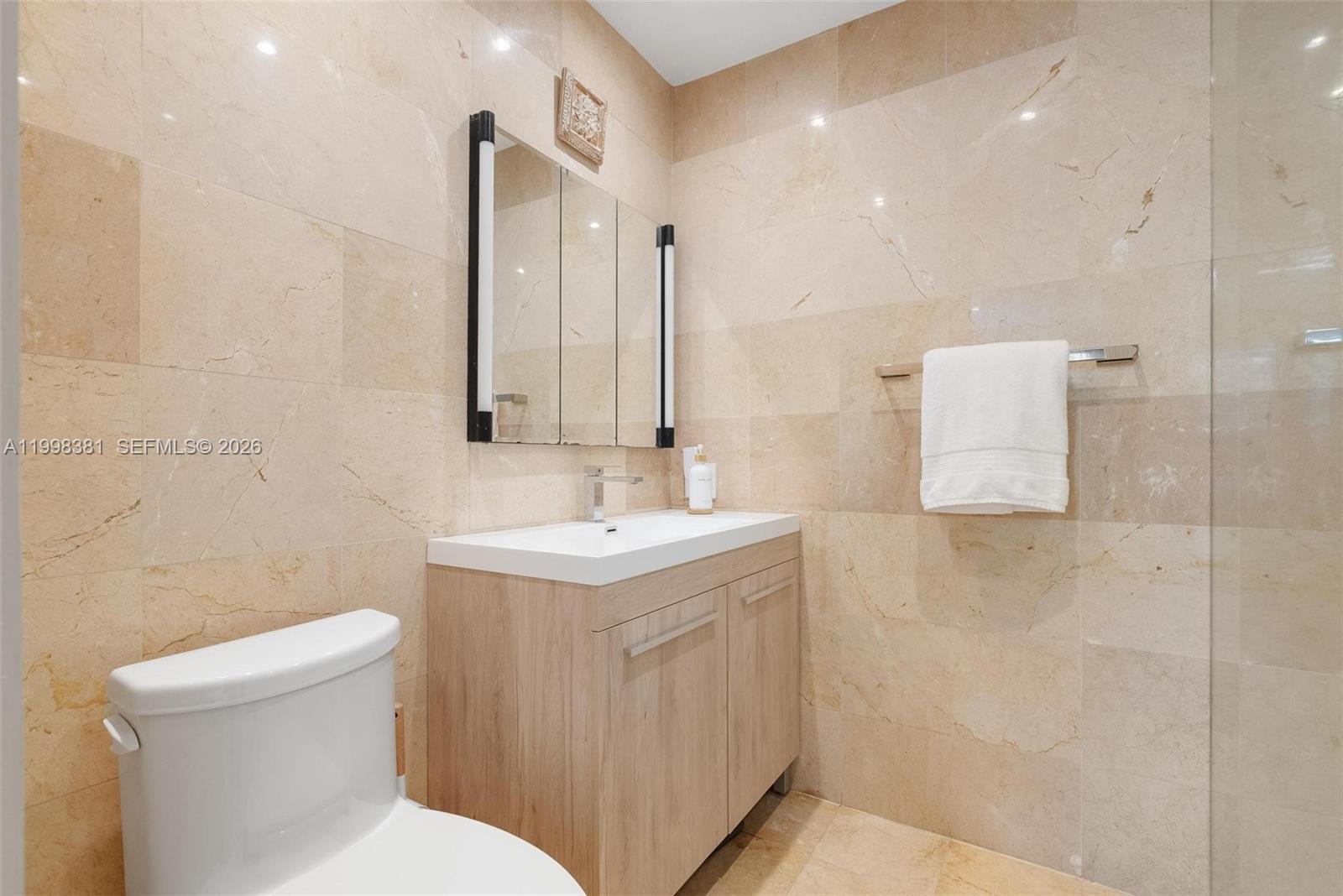 9141 Abbott Avenue Surfside, FL 33154 - Photo 18 of 31 a bathroom with a toilet sink and mirror