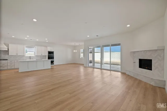 a view of an empty room with wooden floor and a kitchen